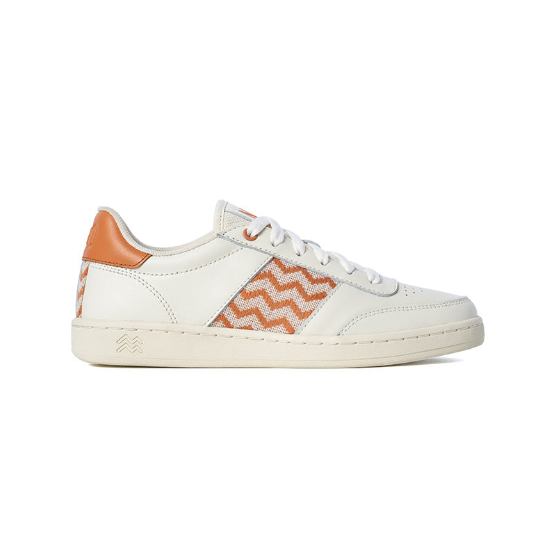 Nachhaltige Sneaker aus beigem Leder mit aprikosenfarbenem Ethno-Muster und weißer Sohle – handgefertigt in Vietnam.