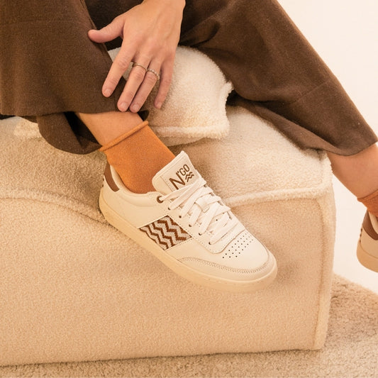 Nachhaltige Sneaker aus beigem Leder mit handgewebtem braunem Ethno-Muster und brauner Gummisohle – fair produziert in Vietnam.