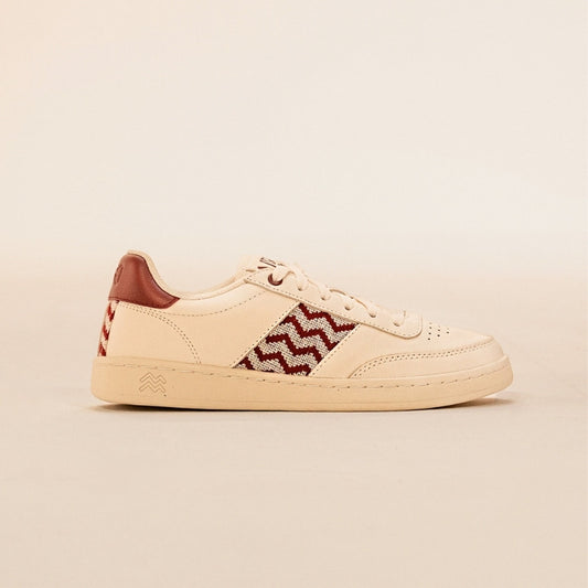 Nachhaltige Sneaker aus beigem Leder mit bordeauxfarbenem Ethno-Muster und weißer Sohle – handgefertigt in Vietnam.