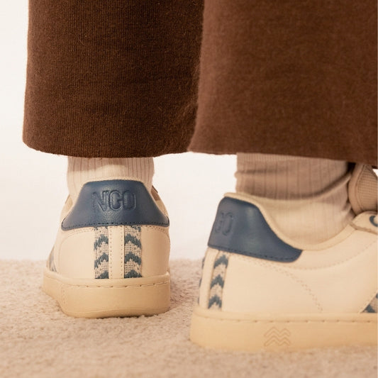 Nachhaltige Sneaker aus beigem Leder mit stahlblauem Ethno-Muster und weißer Sohle – handgefertigt in Vietnam.